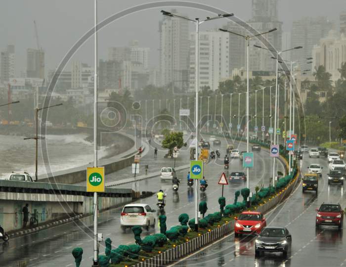 Cars and bikes are seen on a road at Marine Drive during rains, in Mumbai on June 18, 2020.