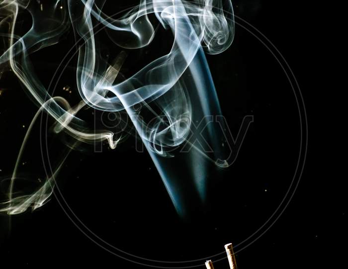 White Puffed Smoke Coming Out Of Sticks In A Dark Background