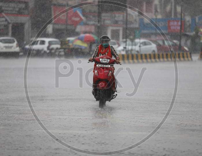 A woman rides a Scooty On The Road During Heavy Monsoon Rain In Prayagraj, June 25, 2020.