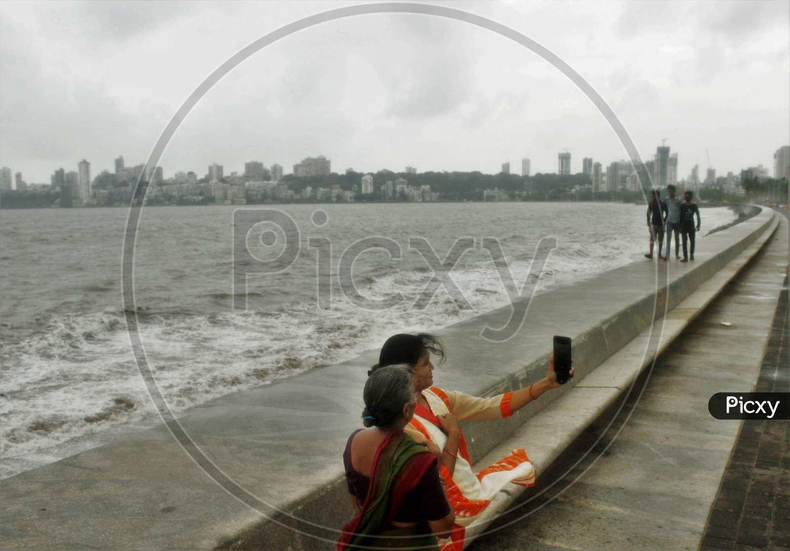 Women take a selfie on the promenade along the Marine Drive on an overcast day,  in Mumbai on June 18, 2020.