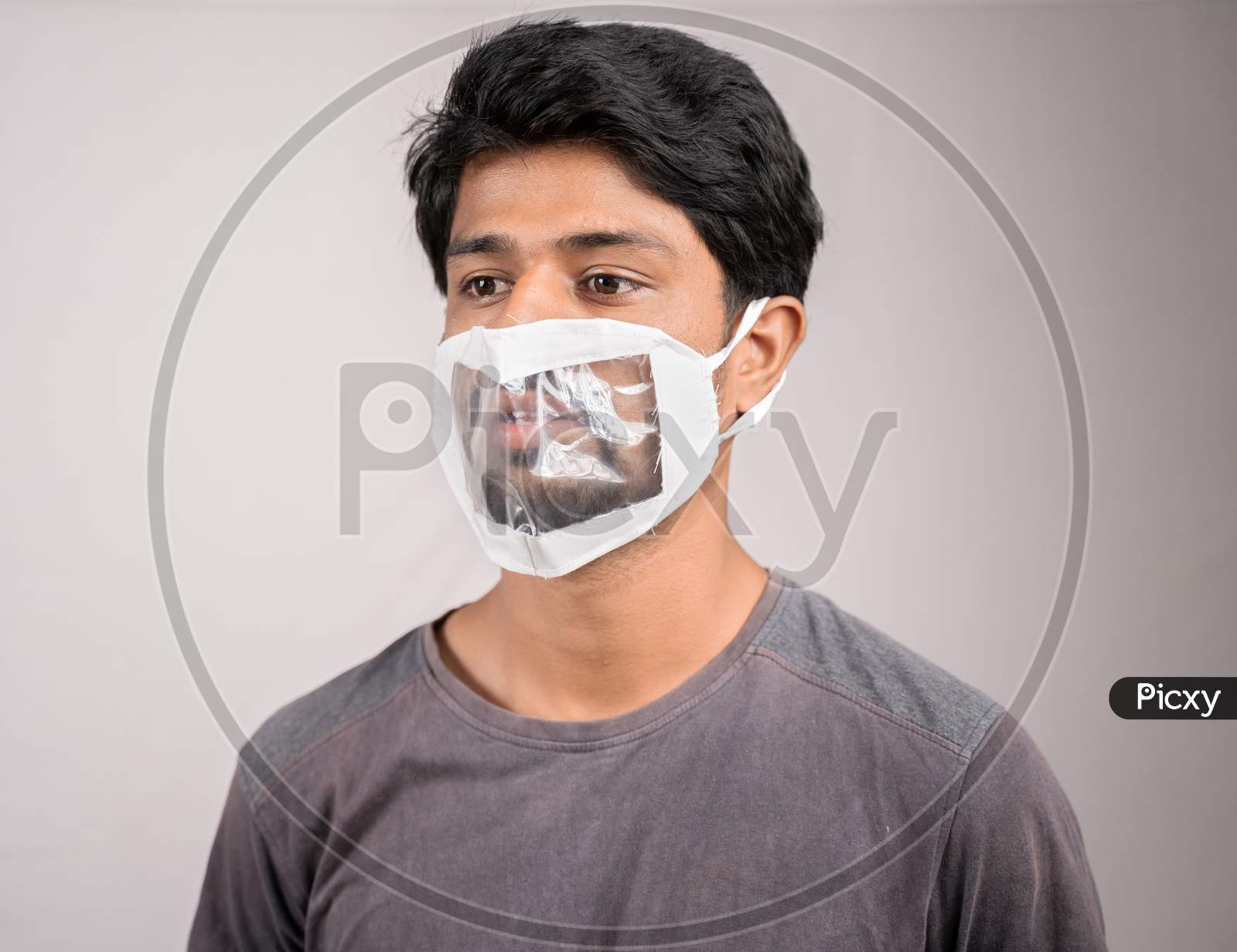 Young Man With Transparent Medical Face Mask, To Help Hearing Imperimeant Or Deaf People To Understand Lipreading During Coronavirus Or Covid-19 Outbreak