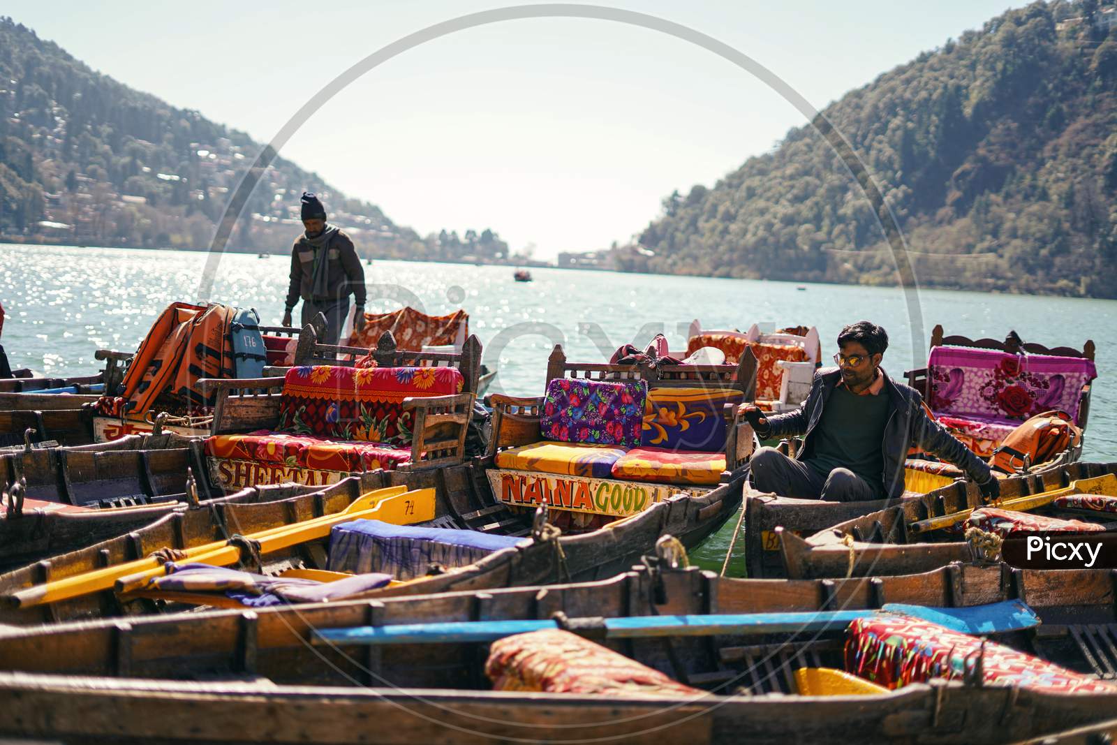 Nainital, Uttrakhand, India- June 24 2020: Two Boatmen Sitting On Colorful Boats On The Shore Of Nainital In Uttrakhand