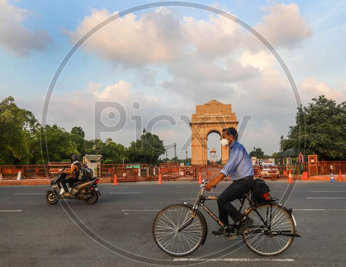 A cyclist wearing a face mask as he pedals in front of India Gate, in New Delhi, India.