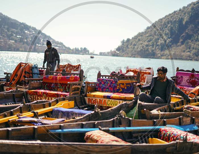 Nainital, Uttrakhand, India- June 24 2020: Two Boatmen Sitting On Colorful Boats On The Shore Of Nainital In Uttrakhand