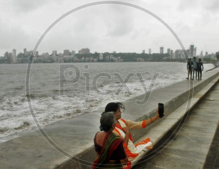 Women take a selfie on the promenade along the Marine Drive on an overcast day,  in Mumbai on June 18, 2020.