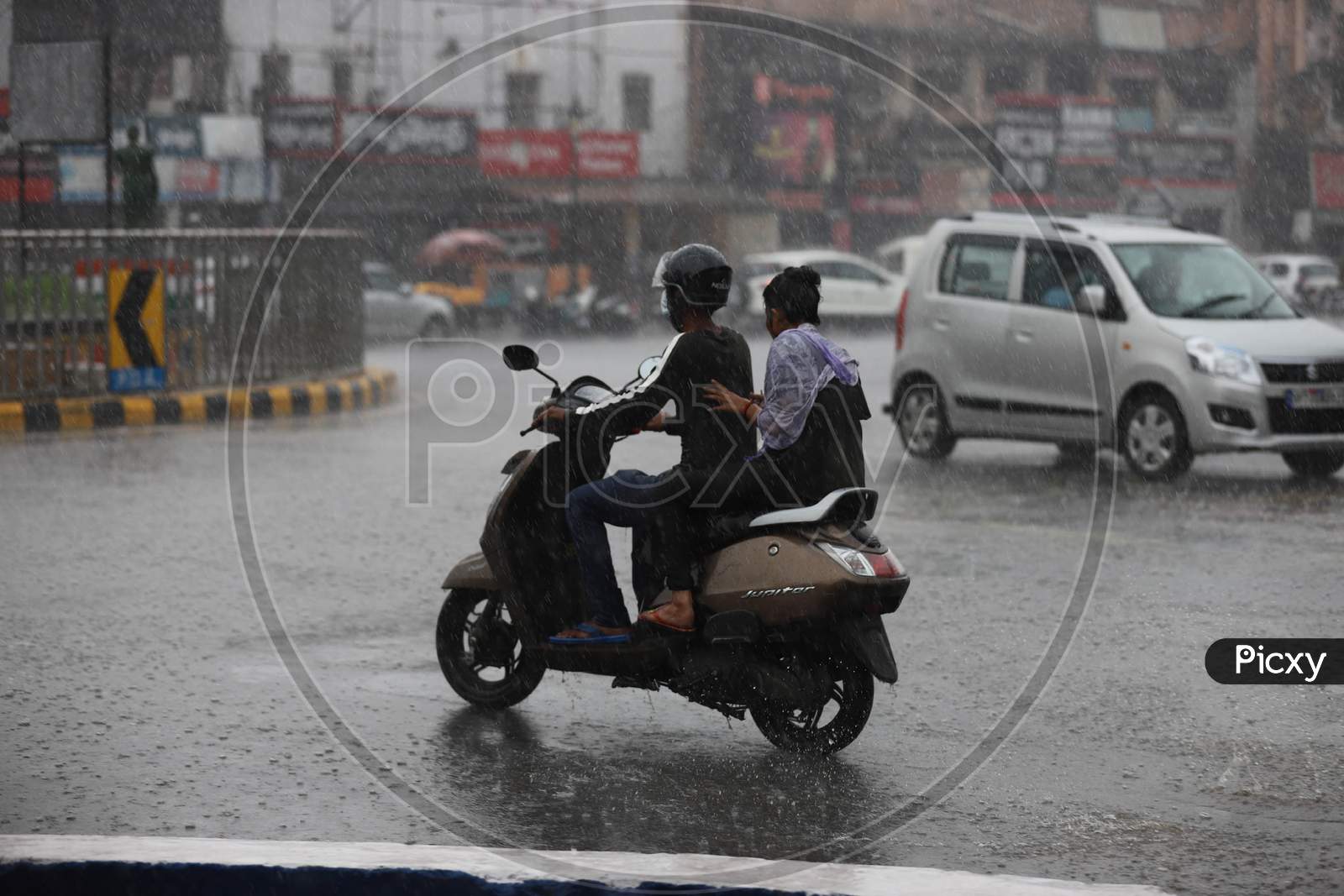 A couple ride a Scooty On The Road During Heavy Monsoon Rain In Prayagraj, June 25, 2020.