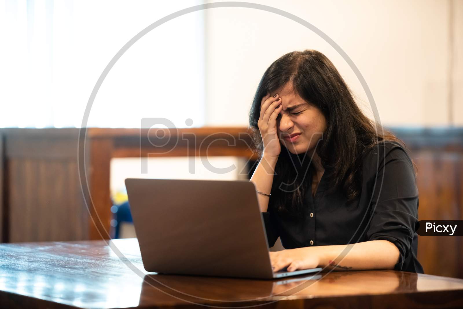 Depressed young Indian girl while working on a laptop