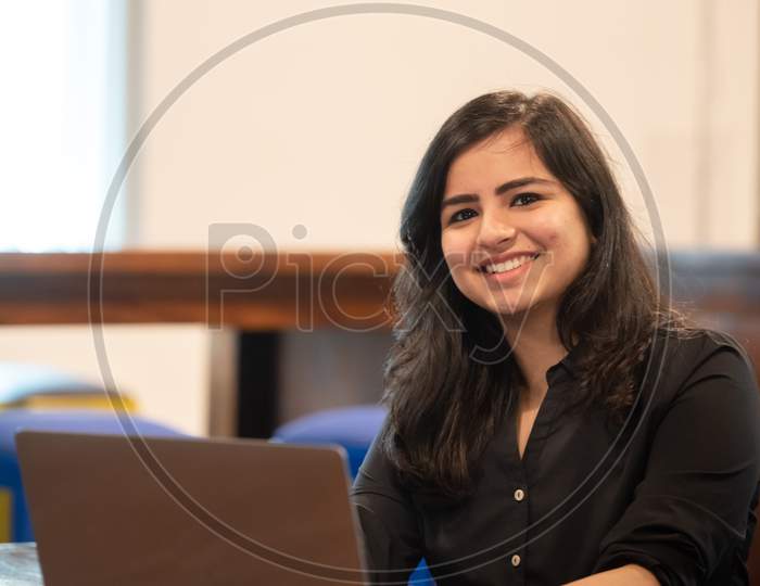 Smiling Young Indian woman working on a Laptop
