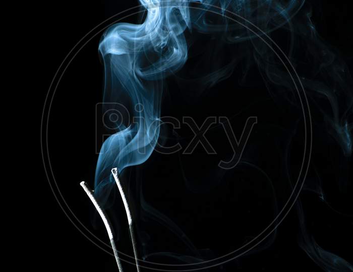 White Puffed Smoke Coming Out Of Sticks In A Dark Background