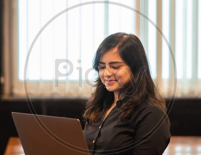 Smiling young Indian woman works on a laptop