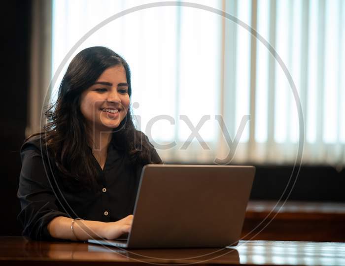 Smiling young Indian girl works on a laptop