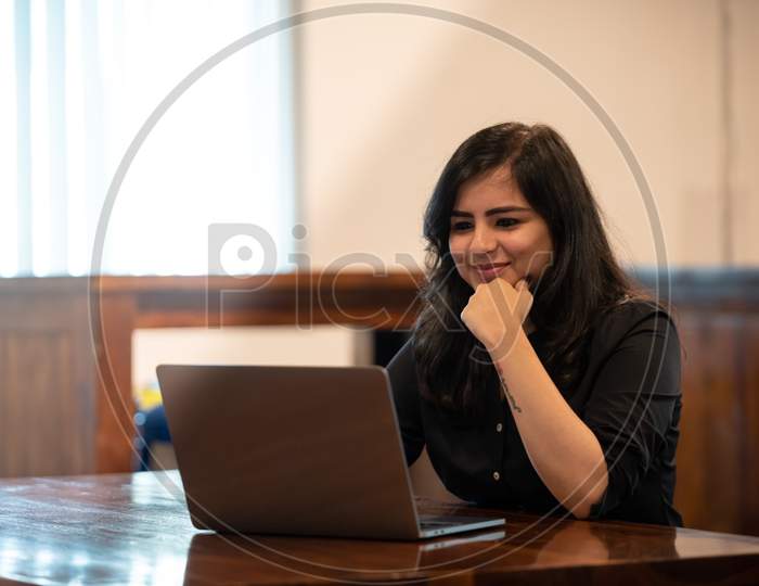 Smiling Young Indian woman working on a Laptop