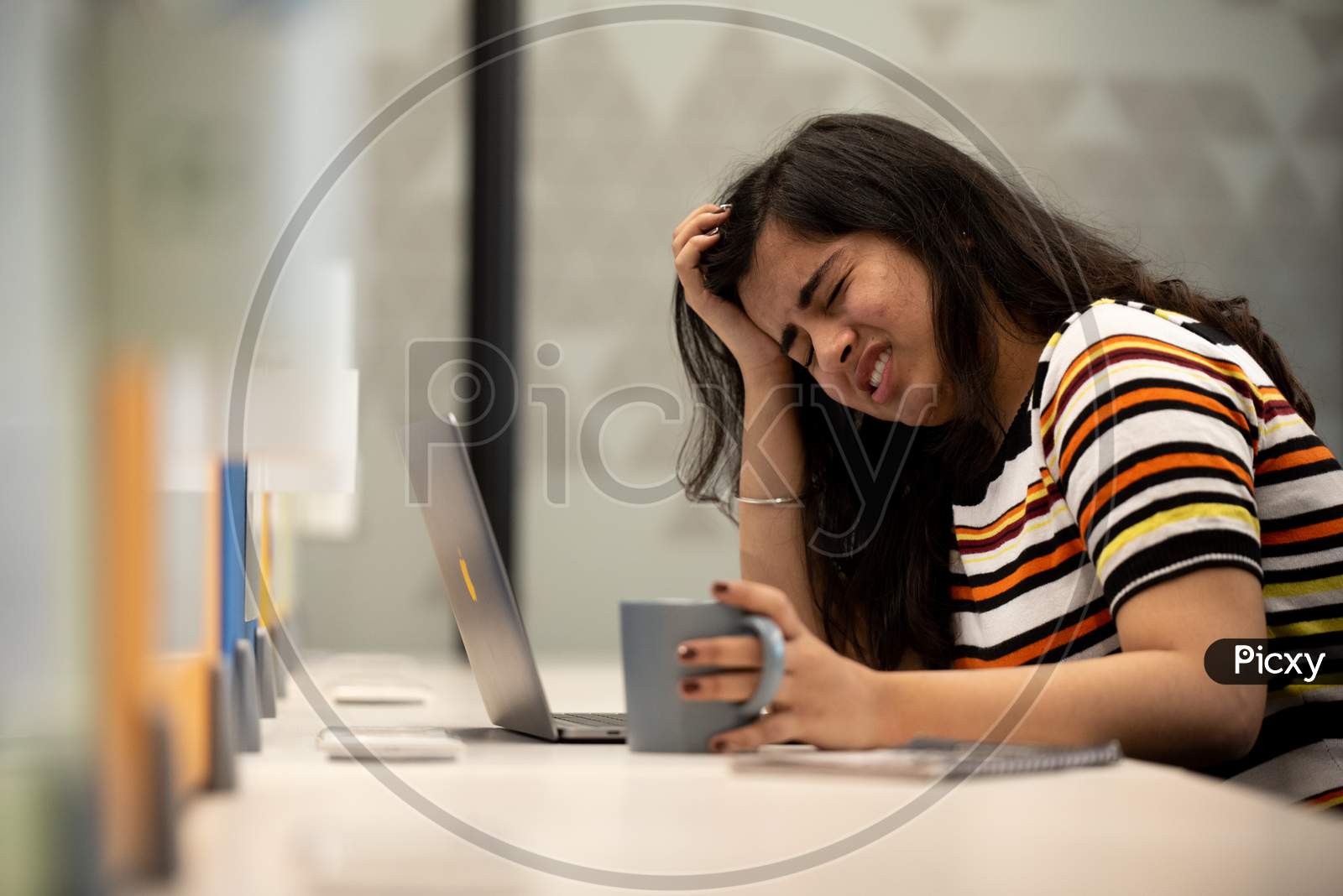 Depressed young Indian working woman crying at work