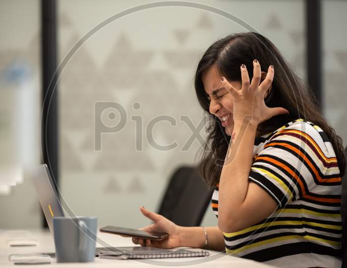 Depressed young working woman crying at work