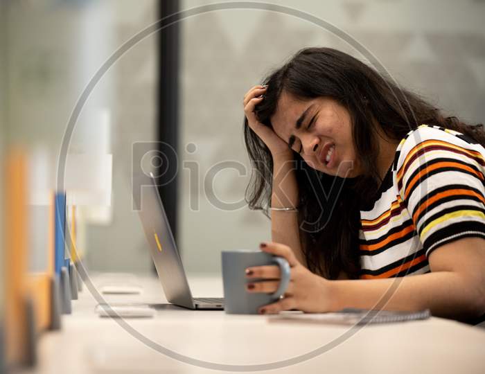 Depressed young Indian working woman crying at work