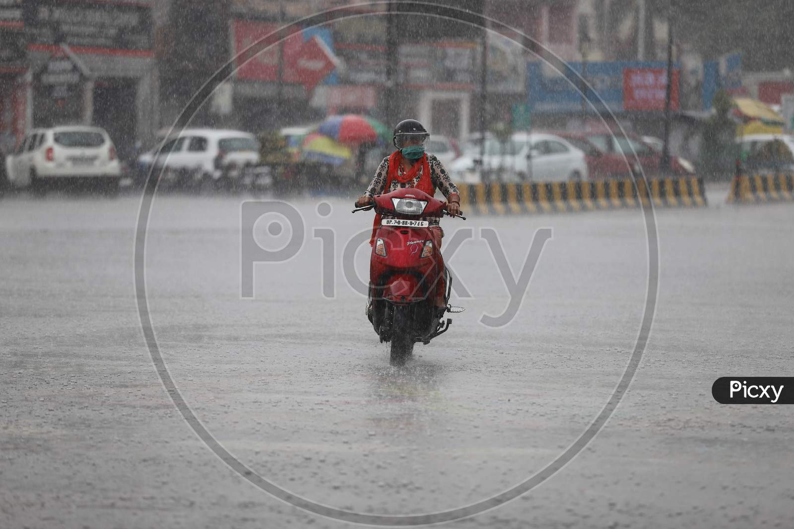 A woman rides a Scooty On The Road During Heavy Monsoon Rain In Prayagraj, June 25, 2020.