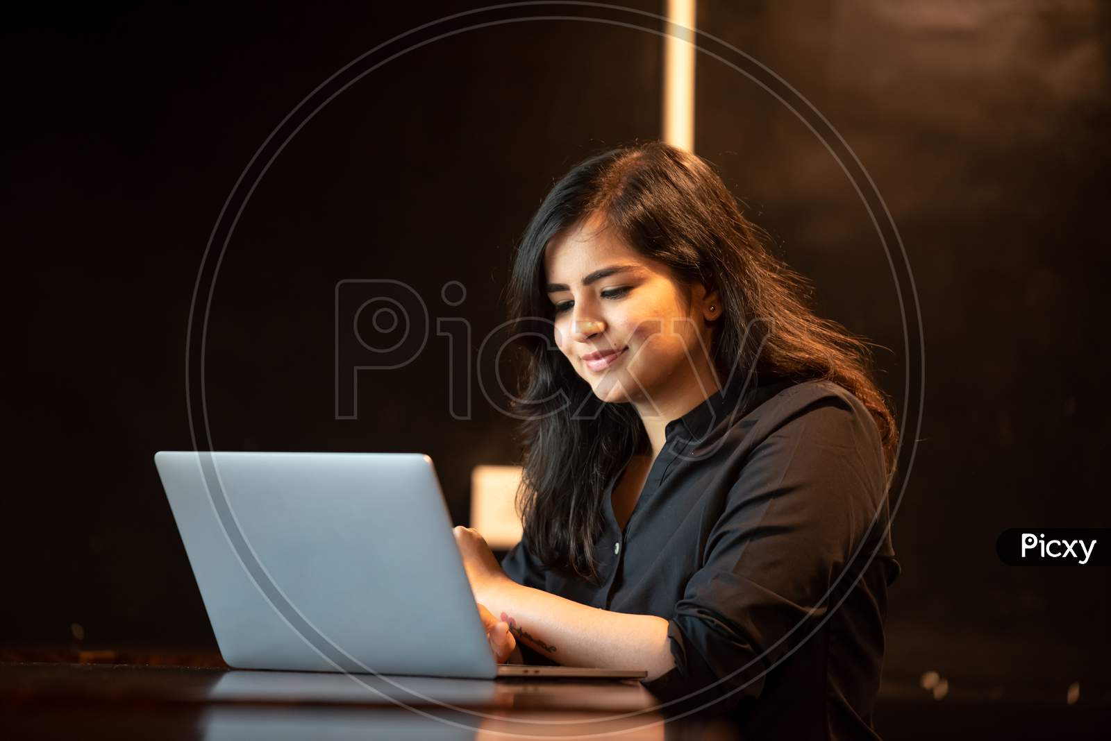 Smiling young Indian girl works on a laptop