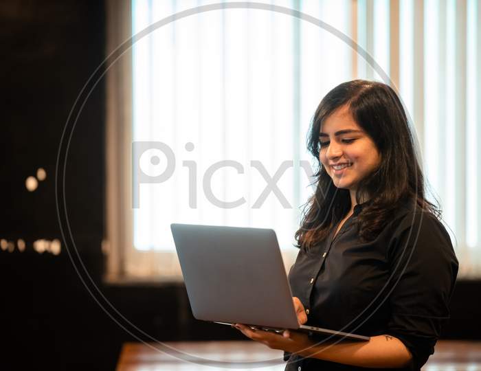 Smiling young Indian woman works on a laptop