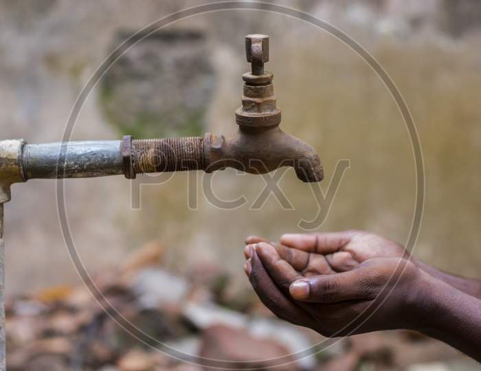 water crisis is a serious threat to India and worldwide,a man holding his hand under the tap for water