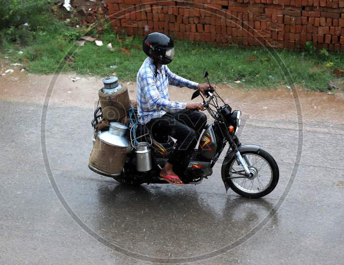 A man rides a bike during rains in Prayagraj, June 26, 2020.