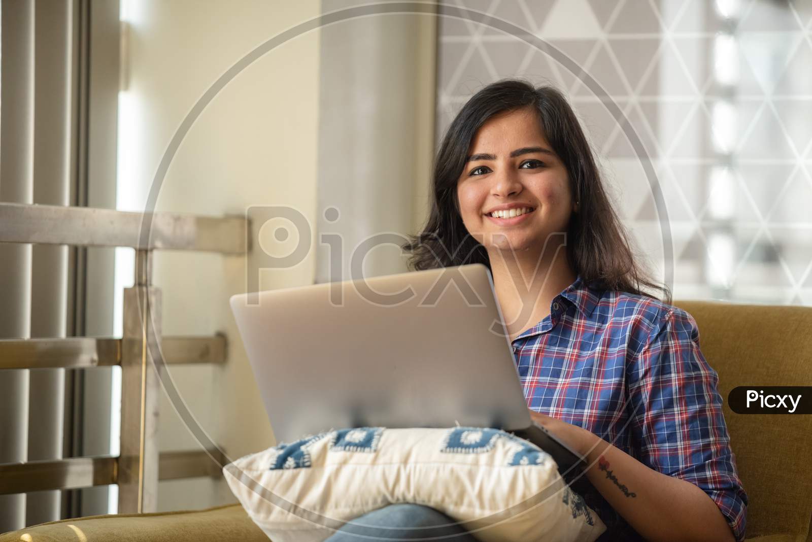 Portrait Of A Beautiful Young And Intelligent Looking Indian Asian Woman Student Wearing A T Shirt Smiling As She Works On Her Laptop