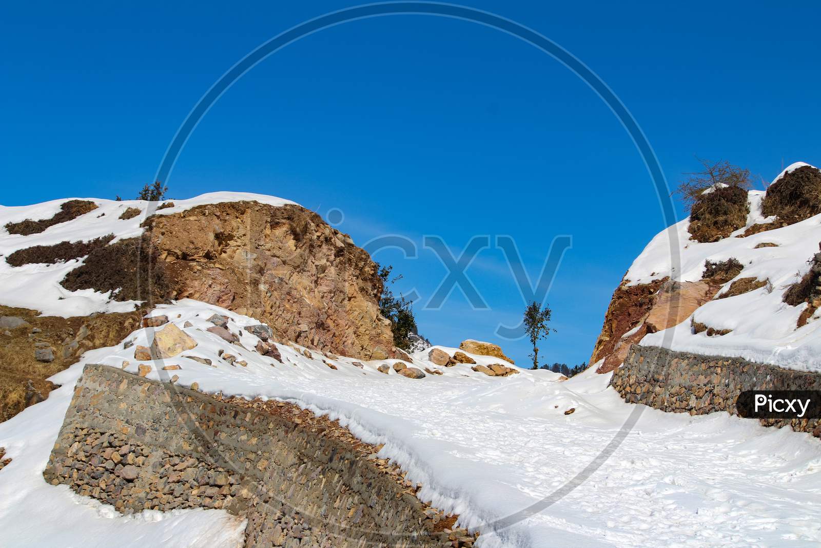 A Path Through Snowy Mountain With Blue Sky
