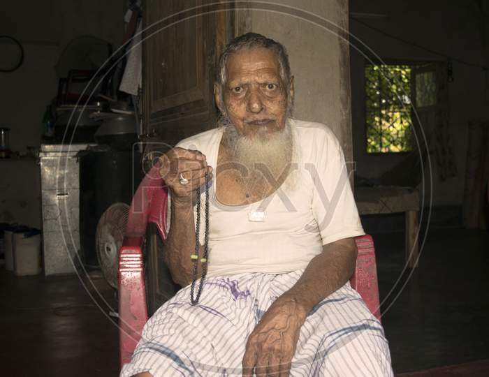 An old Indian bearded person sitting on chair