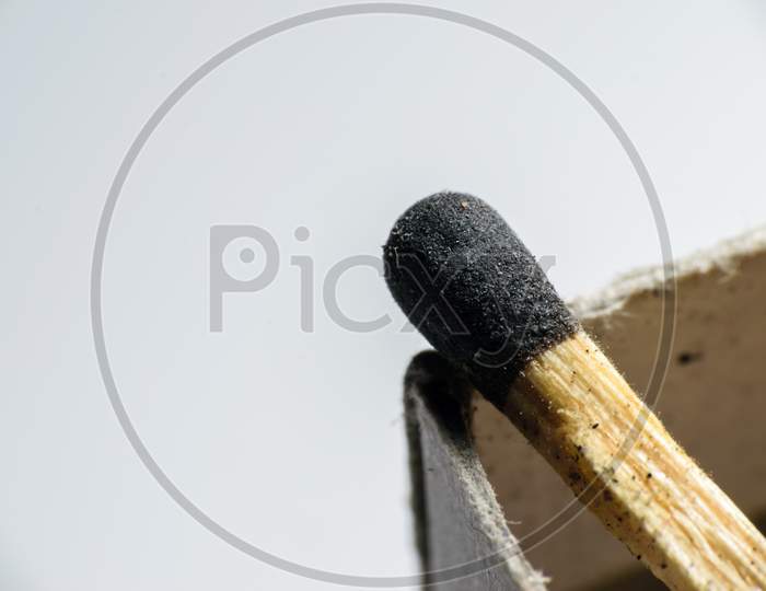 Isolated Match Stick Kept Over The Edge Of A Matchbox In A White Background. Space For Text In Left