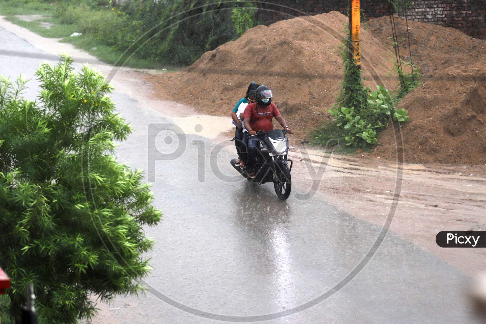 A man rides a bike during rains in Prayagraj, June 26, 2020.