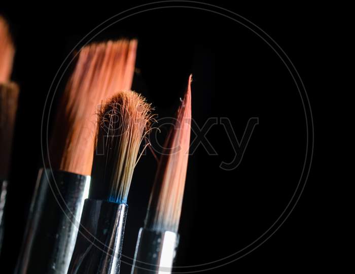Paint Brushes Of Different Size Are Kept Side By Side In A Dark Background. Portrait Mode