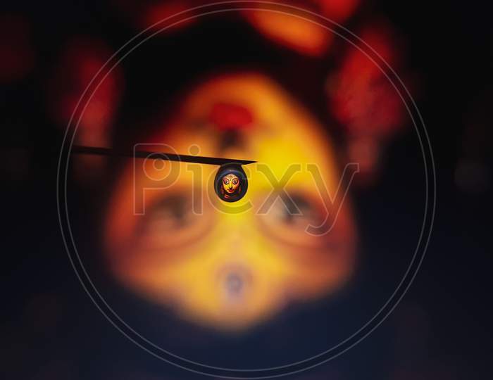 A macro shot of the reflection of Goddess Durga through a water droplet