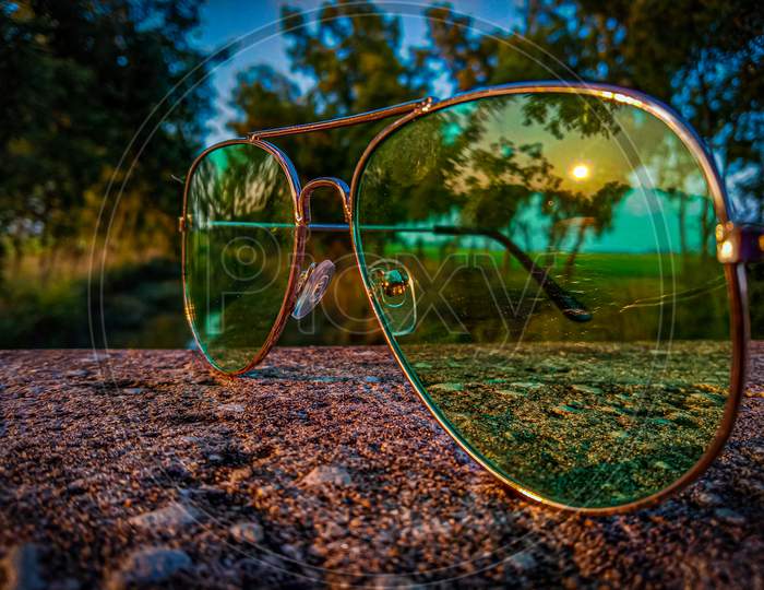 watching sunset through the lens of the sunglass with the beautiful scenery in the background