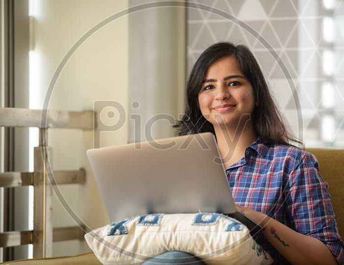 Portrait Of A Beautiful Young And Intelligent Looking Indian Asian Woman Student Wearing A T Shirt Smiling As She Works On Her Laptop