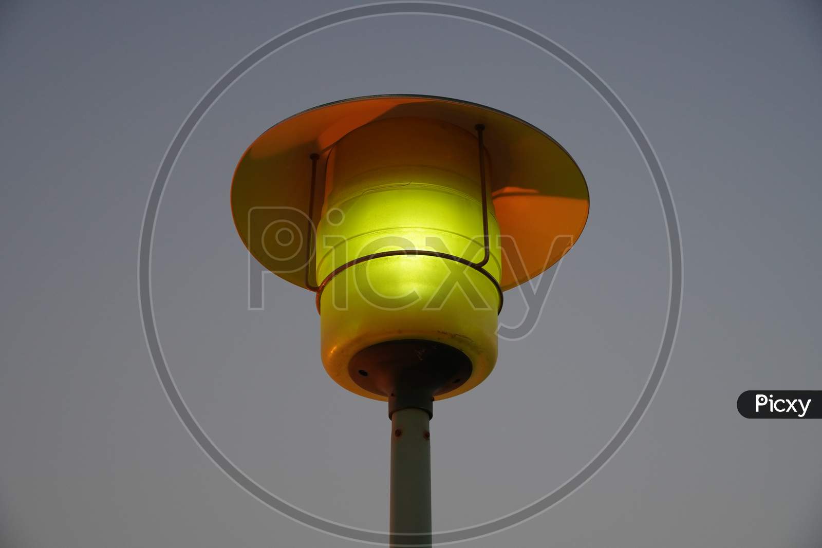 Street Lamp Post With The Evening Skyline View. Outdoor Light Fixture With Sky Background. A Single Hooded Street Light.