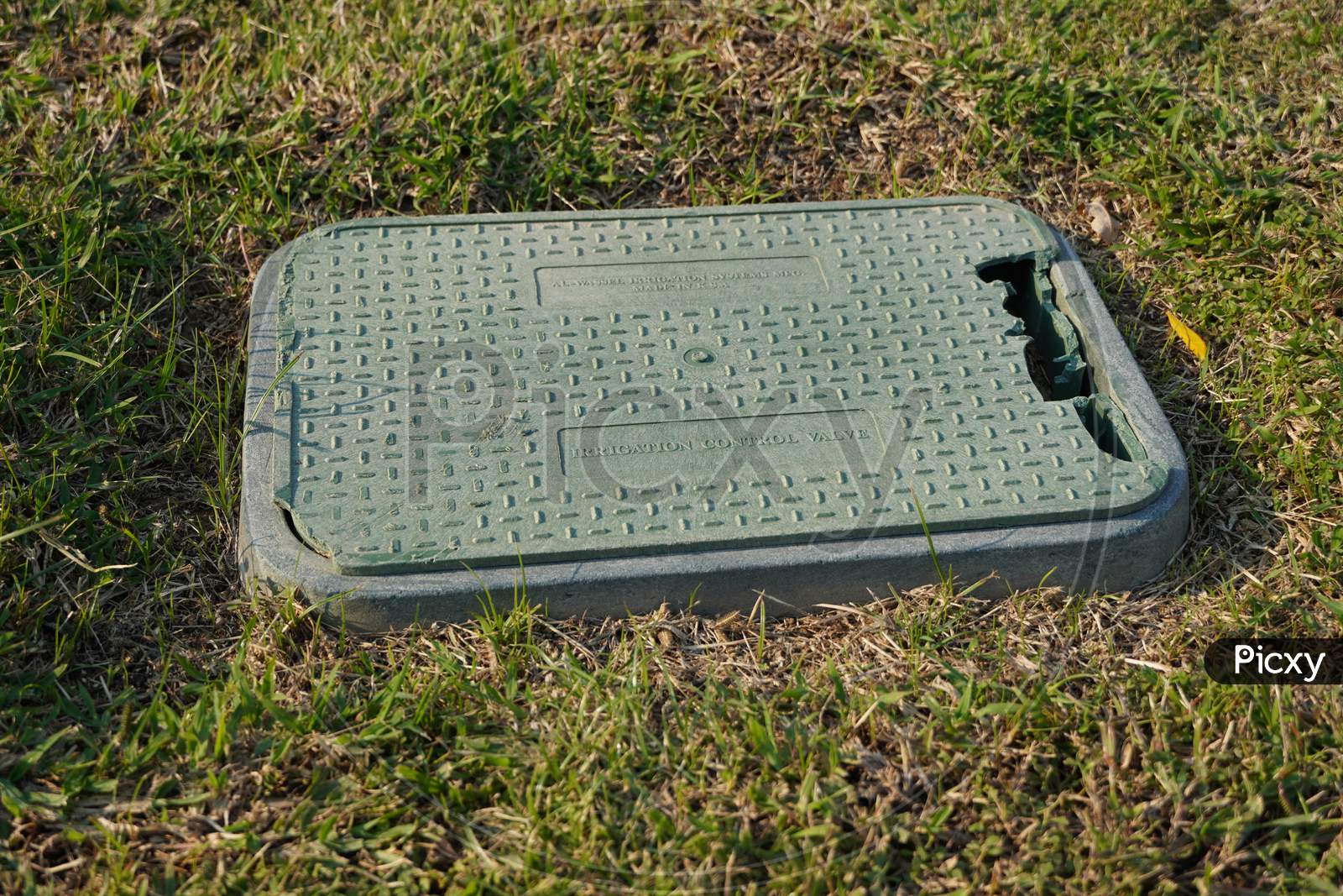 Dubai Uae December 2019 An Old Broken Plastic Box For Irrigation Control Valve With Background Of Dry Green, Brown Grass. Green Valve With Automatic Watering System Installed Under Outdoor Lawn.