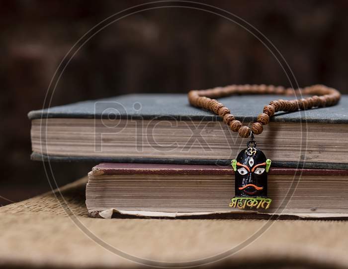 A necklace of brown prayer beads made of wood kept on old books with dark background. Hindu tools for worship. Photo concept for Shivratri