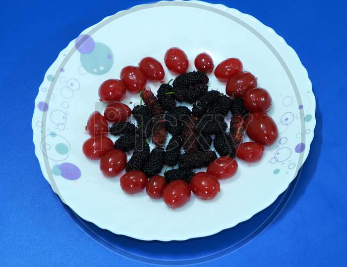 Red berries and mulberry on white plate
