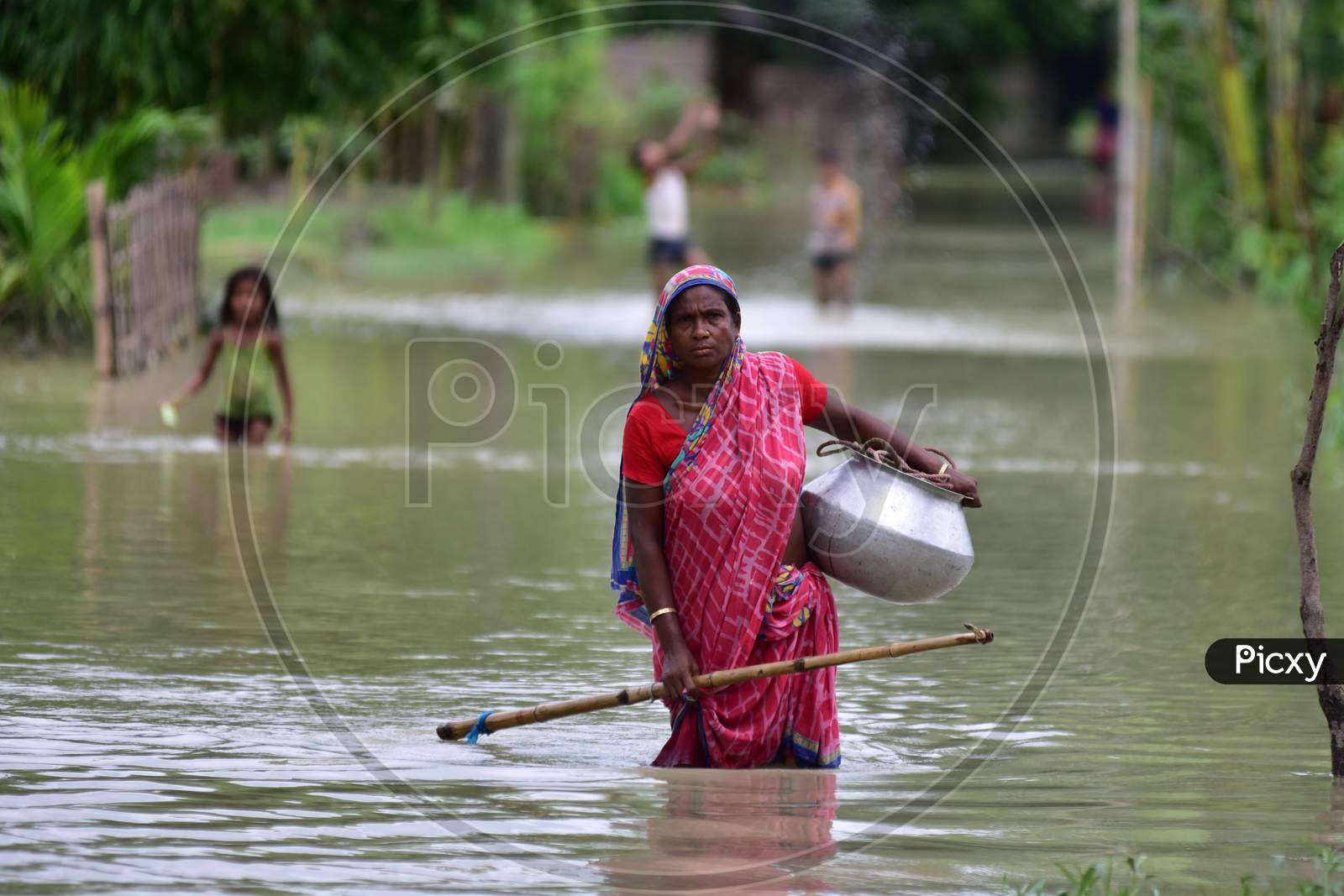 A Woman Wades Through The Floodwaters Following Heavy Rainfall At Bhurbandha Village In Nagaon District Of Assam On June 27,2020.