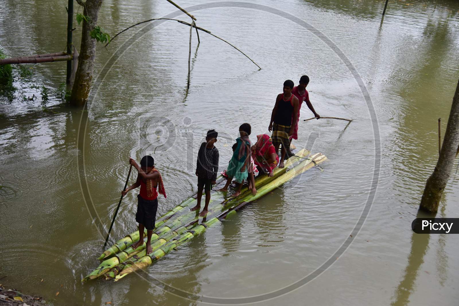 People wade through Floodwaters On A Makeshift Banana Raft Following Heavy Rainfall At Bhurbandha Village In Nagaon District Of Assam On June 27, 2020.