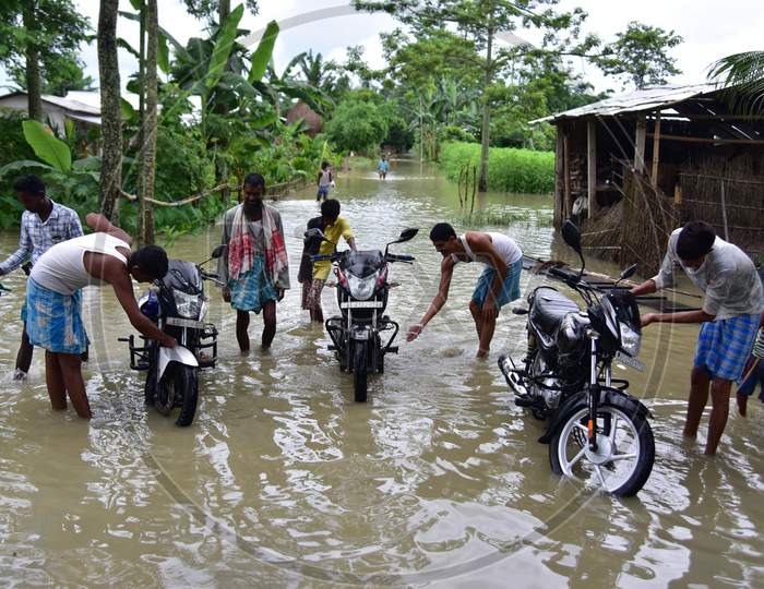 People Clean Their Bike In Floodwaters Following Heavy Rainfall At Bhurbandha Village In Nagaon District Of Assam On June 27,2020.