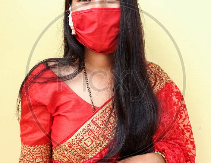 Portrait of beautiful asian girl wearing Indian traditional red color saree with coronavirus mask with selective focus, selective focus on subject, background blur