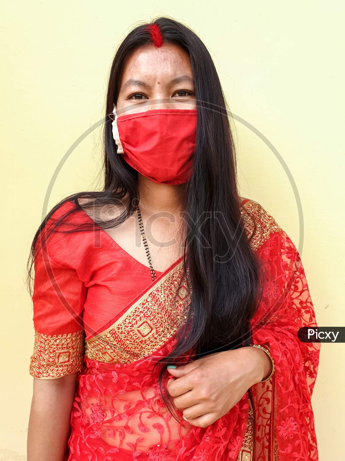 Portrait of beautiful asian girl wearing Indian traditional red color saree with coronavirus mask with selective focus, selective focus on subject, background blur