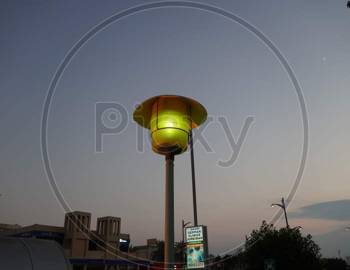 Dubai Uae - November 2019: Street Lamp Post With The Evening Skyline View. Outdoor Light Fixture With Sky Background. A Single Hooded Street Light.