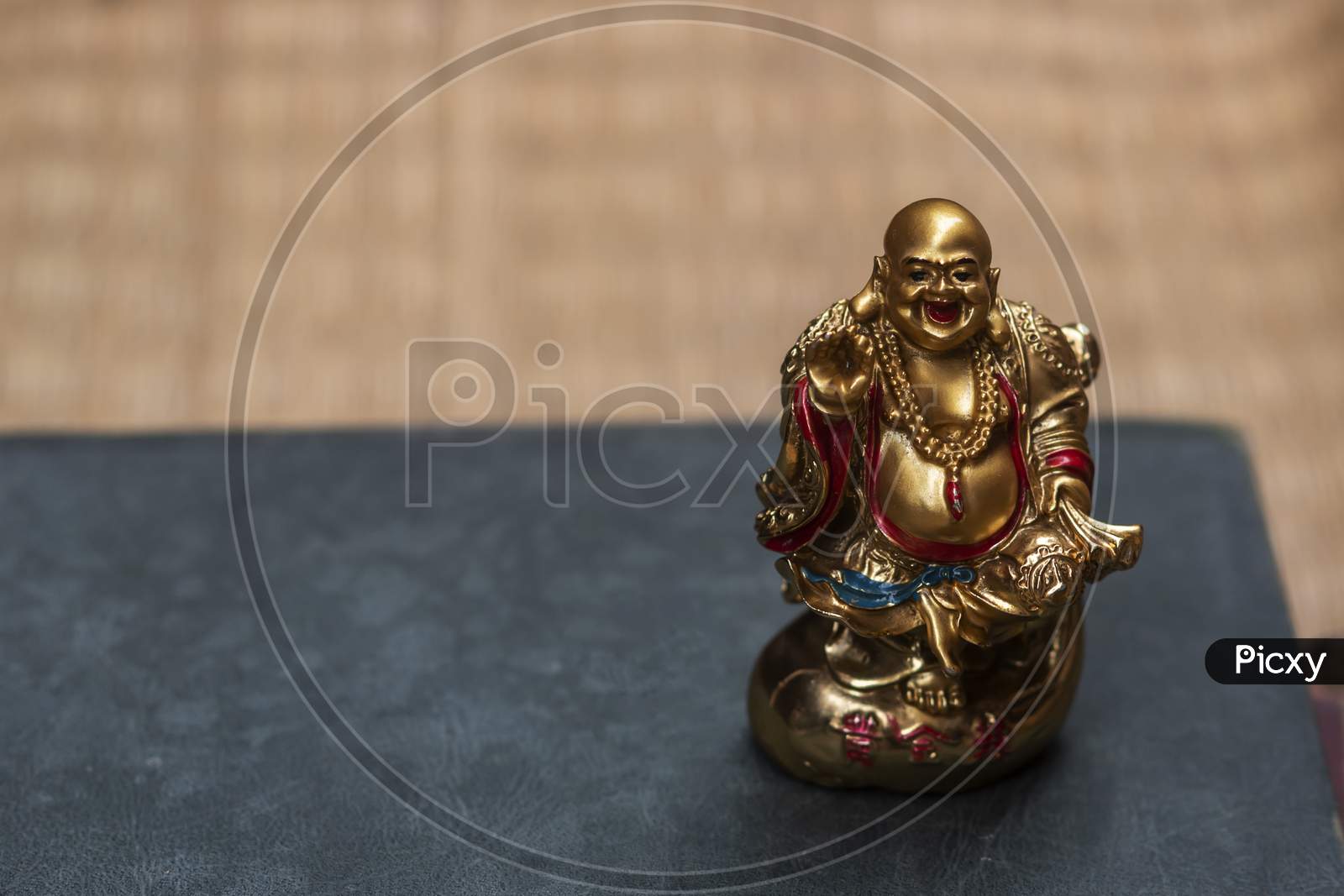 A laughing Buddha kept in a book with jute texture in the background