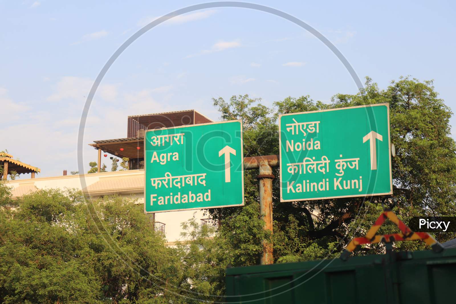 "New Delhi/India -21.06.2020: Sign Board In Green Showing Distance Of Agra , Noida , faridabad and kalindi kunj Texture White  English Language Green Board Near tree "
