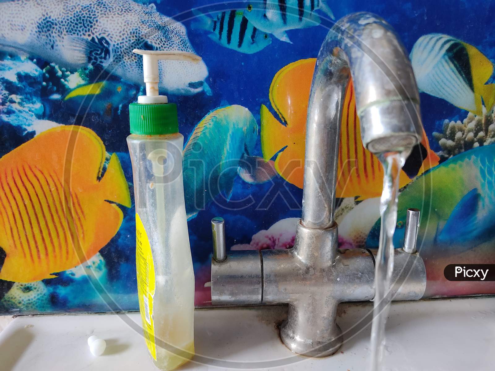 water tap opened with hand sanitizer plastic bottle