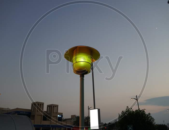 Dubai Uae - November 2019: Street Lamp Post With The Evening Skyline View. Outdoor Light Fixture With Sky Background. A Single Hooded Street Light.