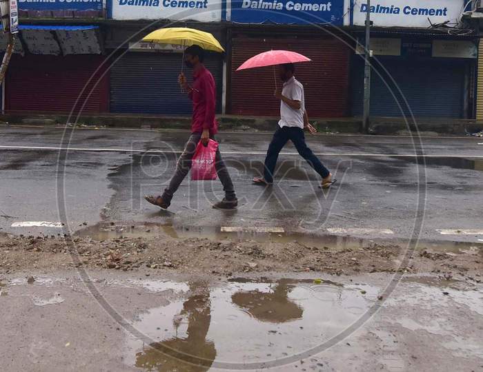 People Walk near Closed Markets During Rains In Nagaon District Of Assam On  Saturday, June 27, 2020. Authority Announced The Imposition Of A Weekend Lockdown In All Urban Areas Of The State