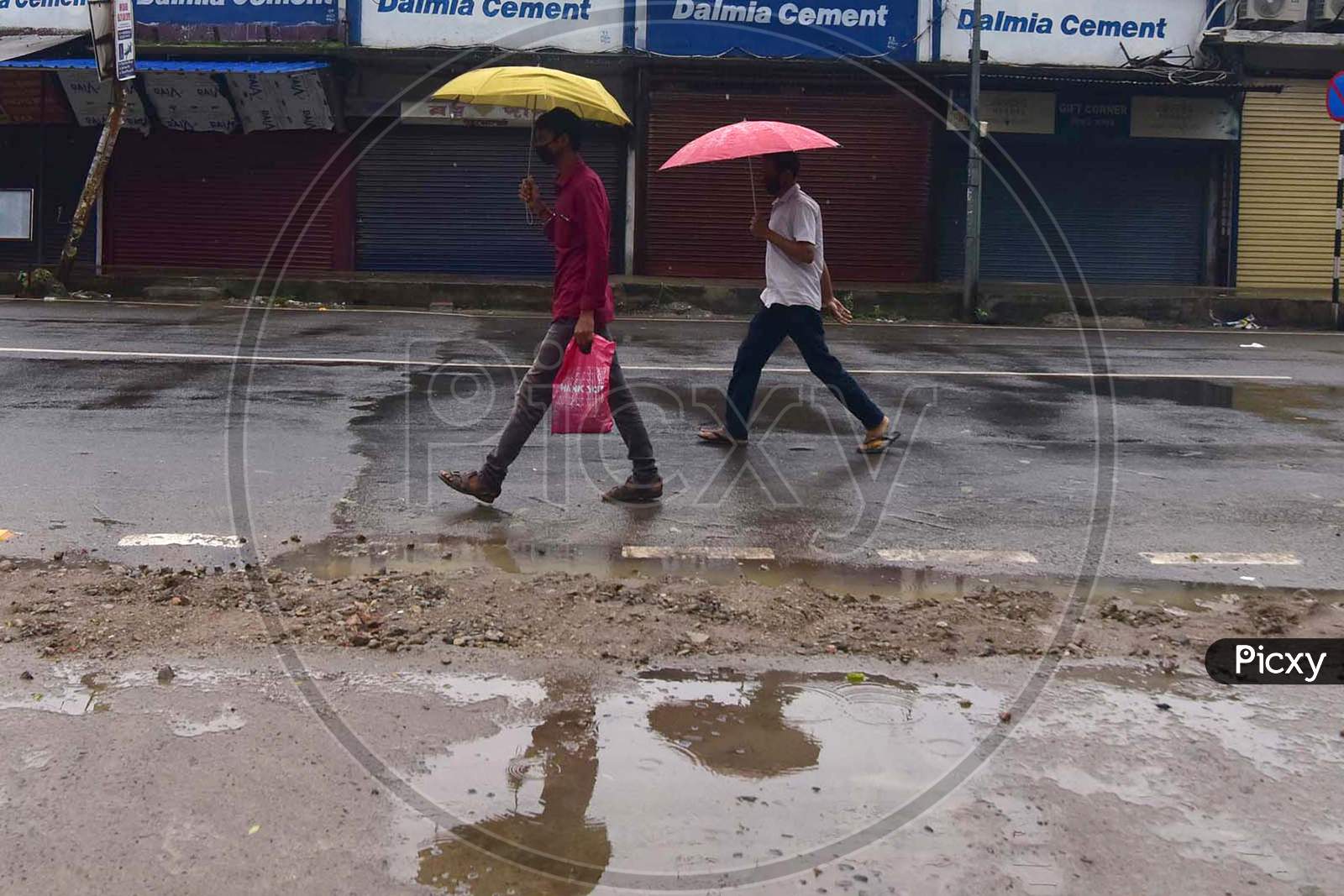 People Walk near Closed Markets During Rains In Nagaon District Of Assam On  Saturday, June 27, 2020. Authority Announced The Imposition Of A Weekend Lockdown In All Urban Areas Of The State