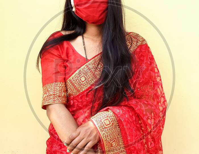 Portrait of beautiful Indian wife wearing Indian traditional red color saree with coronavirus mask